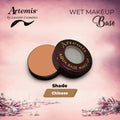Artemis aqua base makeup in open compact, shade Chinese, on pink floral background.