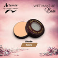 Artemis Aqua Base wet makeup in ivory shade, compact with open lid on a pink floral background.