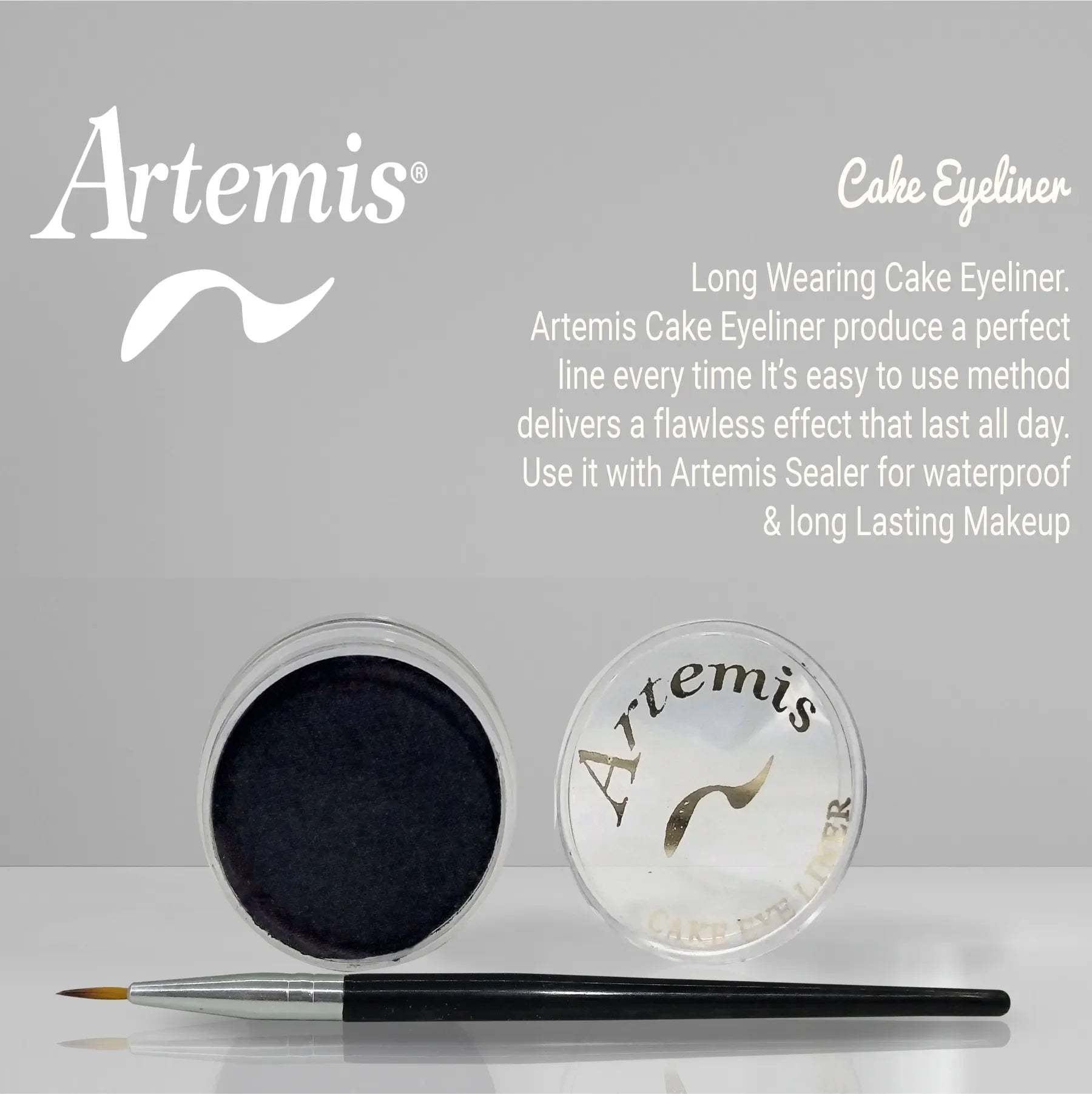 Black cake eyeliner pot with clear lid labeled Artemis and an eyeliner brush on a gray background.