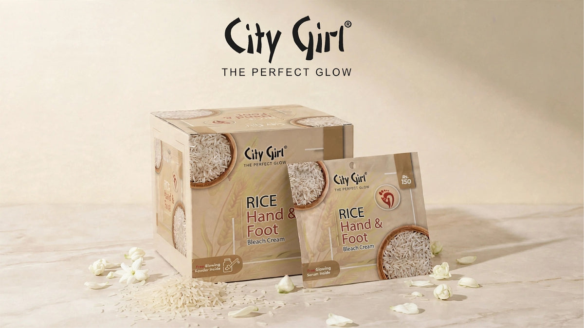 City Girl Rice Hand & Foot Cream packaging displayed on a light beige surface with scattered rice grains and petals. The image shows a cardboard box and an individual packet, with the brand name 'City Girl' and tagline 'THE PERFECT GLOW' printed at the top.
